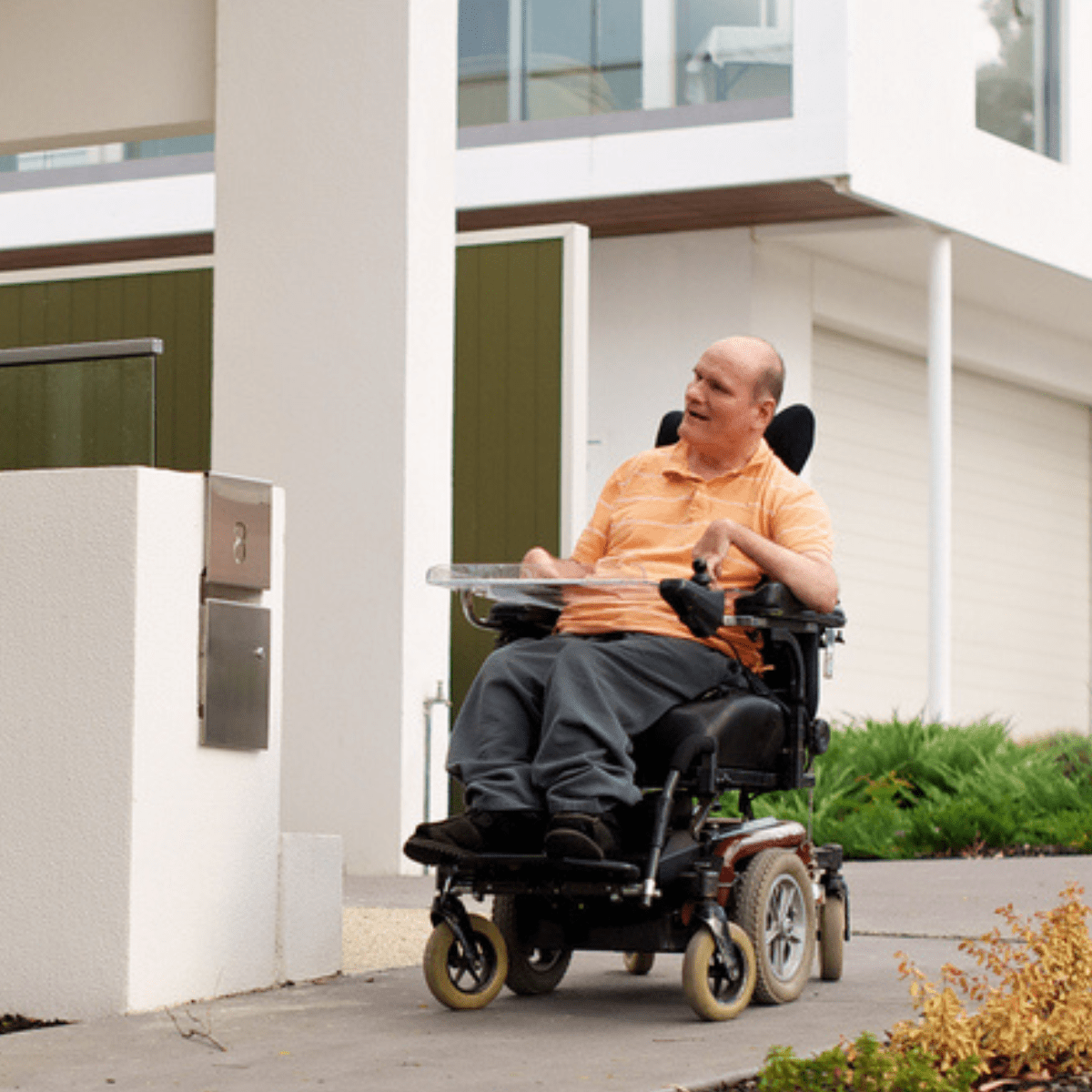 A man in an electric wheelchair outside a residential unit complex